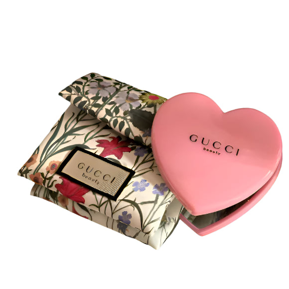 Pink heart-shaped Gucci compact mirror with soft, floral case on a white background