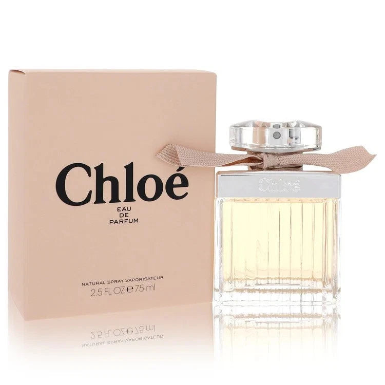 Chloé Eau de Parfum bottle with a clear ribbed glass body and a beige ribbon bow, shown next to its beige packaging box with black Chloé branding.