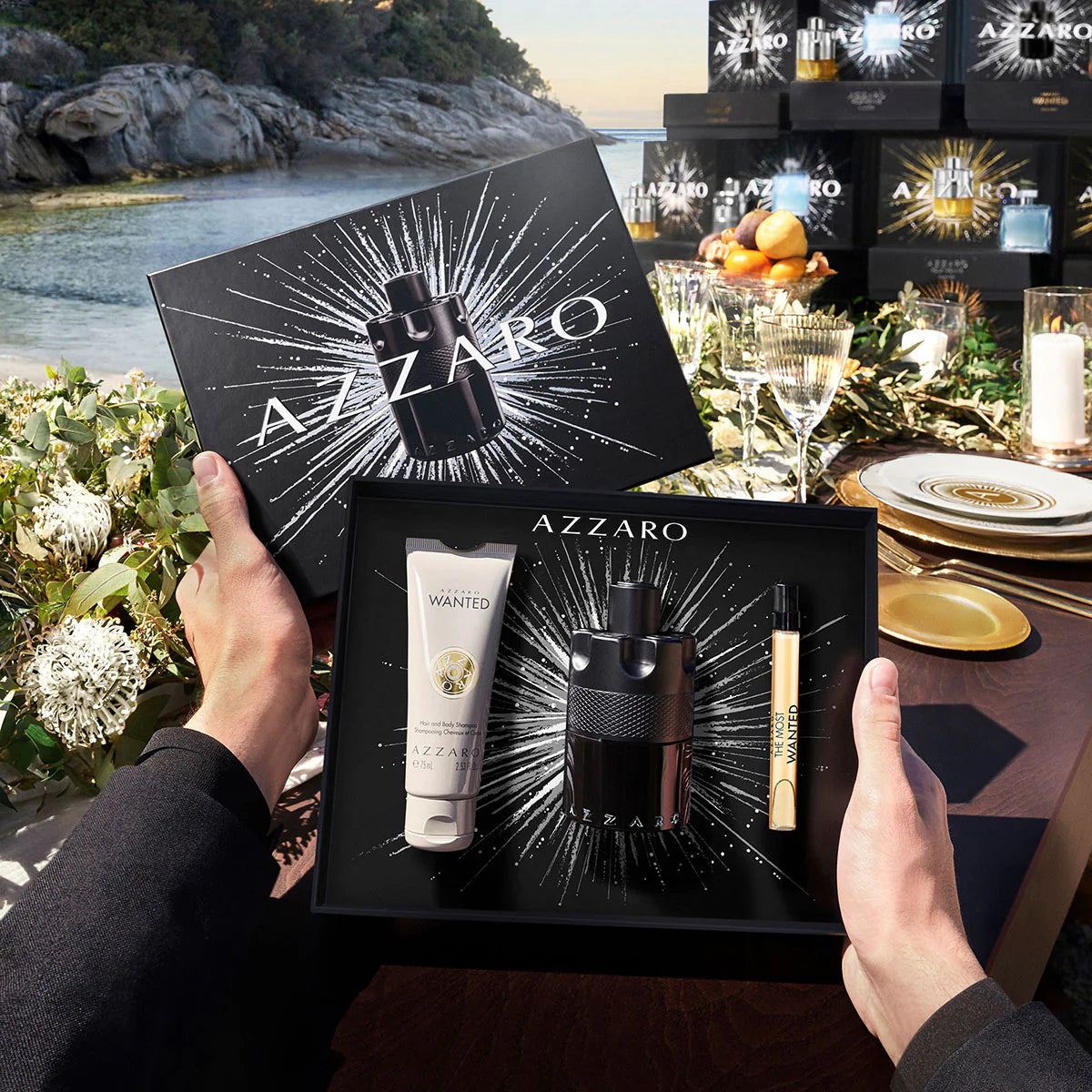 Azzaro The Most Wanted Eau De Parfum Intense set being held over a table with a scenic background