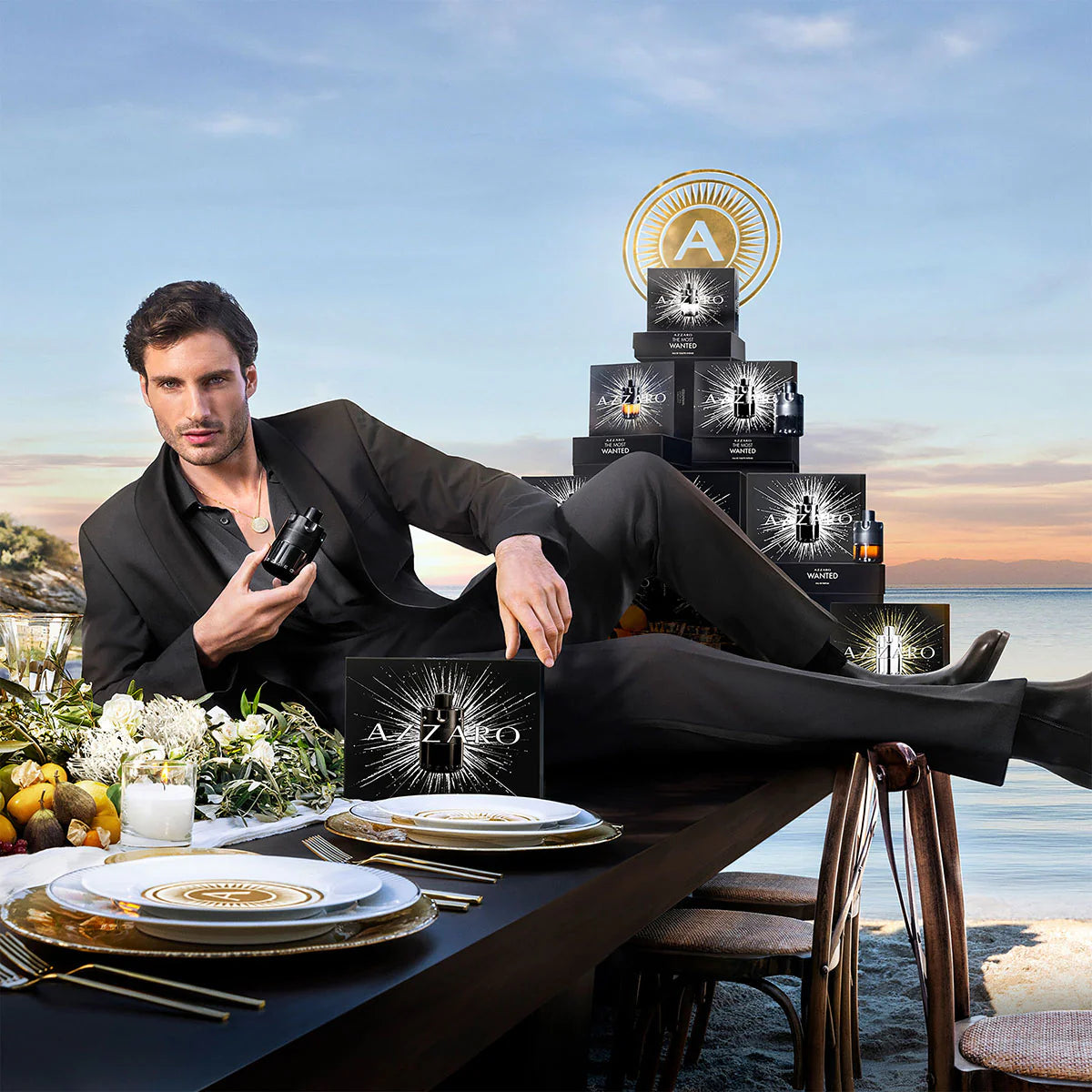 Man in formal attire sitting at a table with Azzaro product packaging in the background
