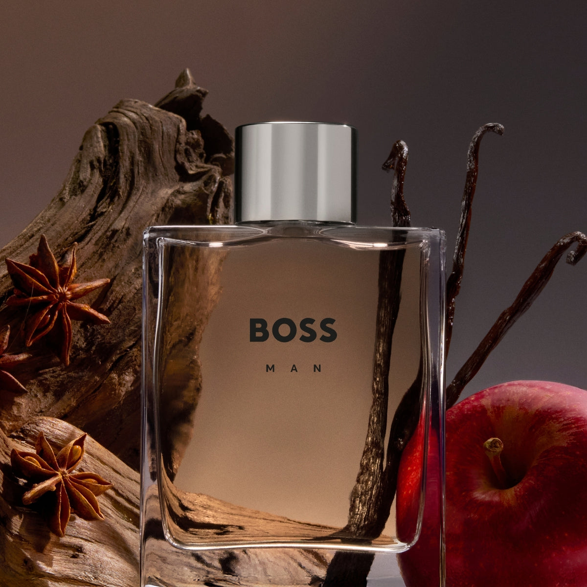 BOSS Man perfume bottle with spices and an apple on a dark background