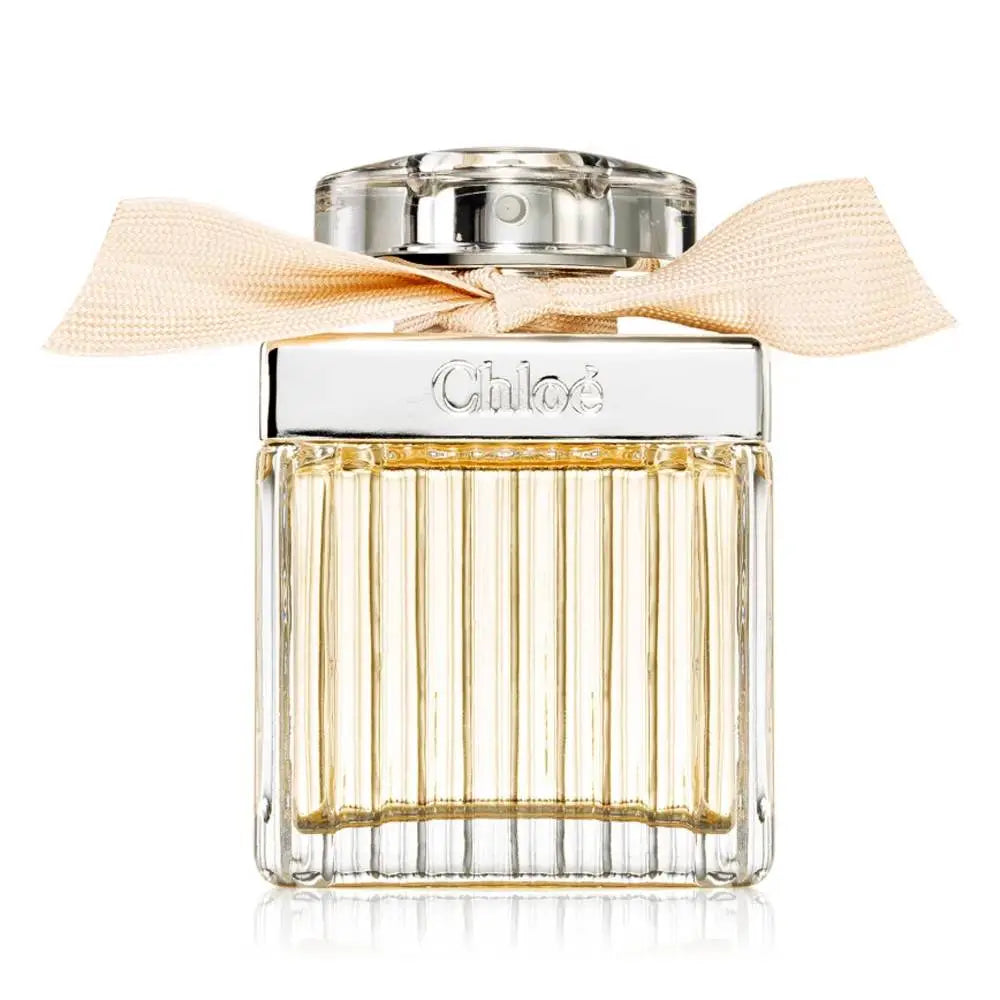 Chloé perfume bottle with a ribbed clear glass body, pale gold liquid, a silver-toned cap, and a beige satin bow tied around the neck, shown on a white background.
