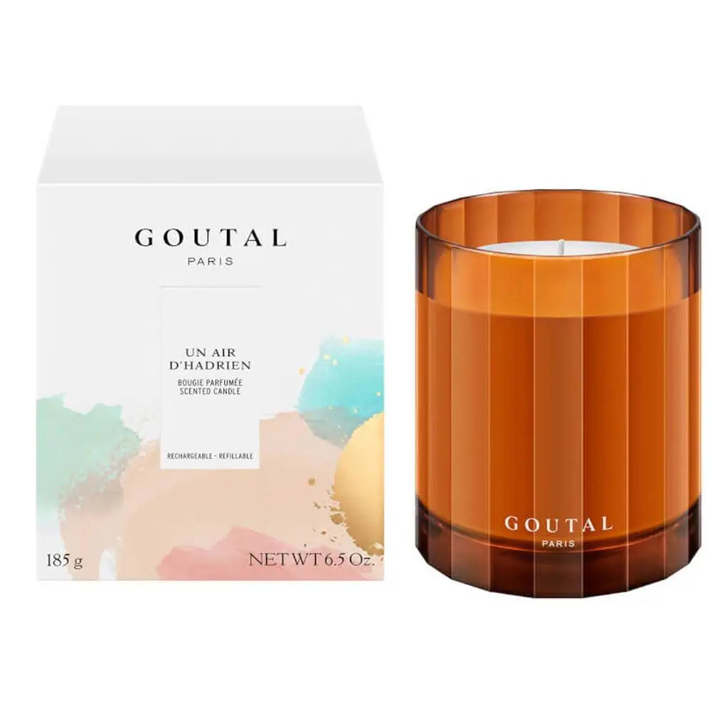 A Goutal Paris scented candle in a faceted amber glass jar next to its white packaging box with pastel watercolor accents.